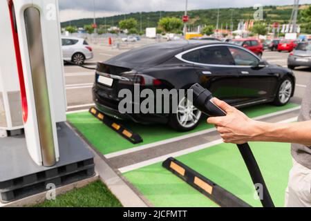 Mann, der den Stecker der Ladestation für Elektroautos hält Stockfoto