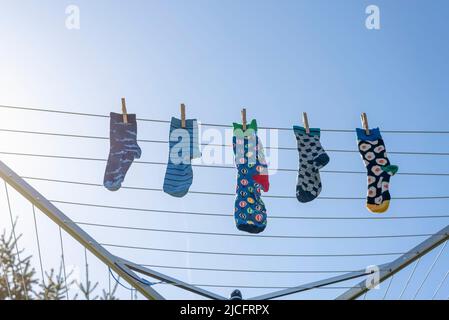 Einsame verschiedene Socken ohne Partner auf einer Wäscheleine, Symbolbild 'Lost Socks Memorial Day'. Stockfoto