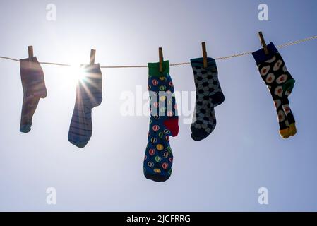 Einsame verschiedene Socken ohne Partner auf einer Wäscheleine, Symbolbild 'Lost Socks Memorial Day'. Stockfoto