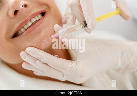 Kosmetikerin Arzt Hände tun Beauty-Verfahren, um ältere weibliche Gesicht mit Spritze Stockfoto