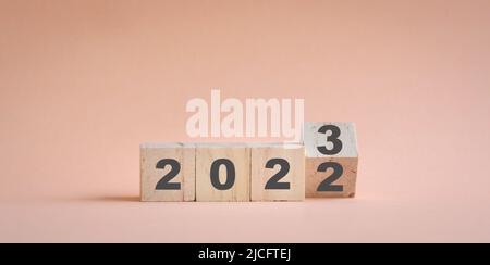 Holzwürfelstock Umdrehen, von 2022 auf 2023. Champagne neutrale Farbe Hintergrund, mit Kopierraum. Stockfoto