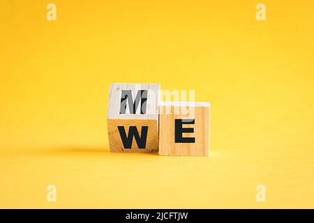 Holzwürfelblöcke wechseln von mir zu uns. Teamwork-Konzept. Auf gelbem Hintergrund. Stockfoto