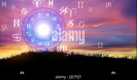Astrologische Tierkreiszeichen innerhalb des Horoskopkreises. Sonne über dem Tierkreisrad und Sonnenaufgang im Hintergrund. Die Macht des Universums Konzept. Stockfoto