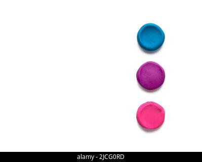 Drei Farben Modellierung Ton Plastilin Finger strukturiert flach Kugeln isoliert auf weißem Hintergrund. Draufsicht, Kopierbereich. Stockfoto