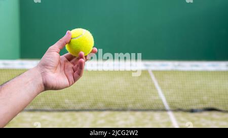 Monitor mit Paddle-Tennisball für den Padel-Unterricht an einen kaukasischen Schüler auf einem grünen Tennisplatz im Freien. Männlicher Spieler, der ein Spiel in der spielt Stockfoto