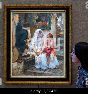 London, Großbritannien. 13. Juni 2022. Ein Mitarbeiter präsentiert „New Shoes, Algier“ von Frederick Arthur Bridgman (Est. £100.000-150.000) bei einer Vorschau auf den Orientalistischen Kunstverkauf von Bonhams. Die Auktion findet am 14. Juni in den Galerien der Bonhams New Bond Street statt. Kredit: Stephen Chung / Alamy Live Nachrichten Stockfoto