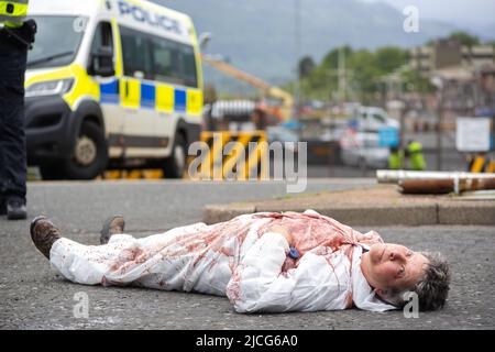 Coulport, Argyll, Schottland 13. Juni 2022 fünf ehemalige Greenham-Frauen und drei Mitglieder von Peace Pirates, einem Ableger von Trident Plowshares, führen eine Blockade im nuklearen Sprengkopflager von Coulport durch. Die ‘Greenham goss gefälschtes Blut auf sich selbst und inszenierten einen Einfall vor den Toren, der eine Seite des Eingangs in die Basis blockierte, während die Mitglieder von ‘Peace Pirates’ (pensionierter Lehrer Brian Quail, 84, mit einer Herztransplantation und durch einen kürzlichen Schlaganfall behindert, Willemien Hoogendorf aus Holland und Gillean Lawrence, eine Großmutter und Unterstützer von XR Peace) sperrten den Kreisverkehr weiter ein Stockfoto