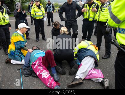 Coulport, Argyll, Schottland 13. Juni 2022 fünf ehemalige Greenham-Frauen und drei Mitglieder von Peace Pirates, einem Ableger von Trident Plowshares, führen eine Blockade im nuklearen Sprengkopflager von Coulport durch. Die ‘Greenham goss gefälschtes Blut auf sich selbst und inszenierten einen Einfall vor den Toren, der eine Seite des Eingangs in die Basis blockierte, während die Mitglieder von ‘Peace Pirates’ (pensionierter Lehrer Brian Quail, 84, mit einer Herztransplantation und durch einen kürzlichen Schlaganfall behindert, Willemien Hoogendorf aus Holland und Gillean Lawrence, eine Großmutter und Unterstützer von XR Peace) sperrten den Kreisverkehr weiter ein Stockfoto