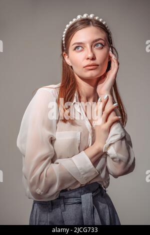 Stilvolle junge Frau in weißen Casuals wegschauen und lächeln. Vertikal Stockfoto