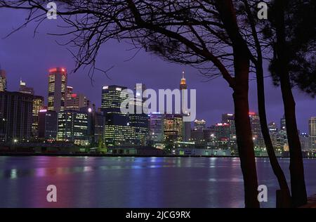 Sydney Tower, Central Sydney und Darling Harbour in der Abenddämmerung von Illoura Reserve, Pfau Point, Balmain East, Sydney, NSW, Australien: Helle Lichter und Reflexionen Stockfoto