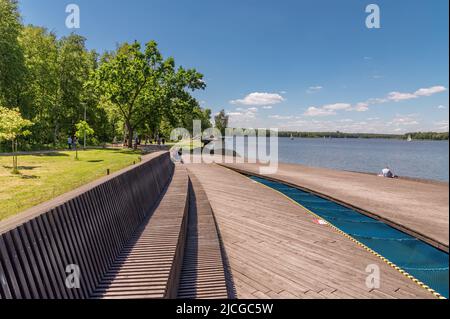 Tychy, Schlesien, Polen: Parpocany See an einem ruhigen Samstagmorgen mit Menschen, die sich auf einer Holzterrasse am See entspannen Stockfoto