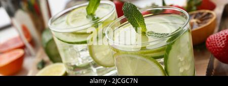 Ein paar leckere erfrischende Cocktails mit Zitronen- und Gurkenscheiben, die mit Minze verziert sind Stockfoto