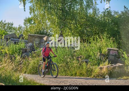 Aktive ältere Frau mit Elektro-Mountainbike auf Tour zum Birkenkopf, einem Gipfel aus Trümmern des 2. Weltkrieges, hoch über der Stadt Stuttgart, Deutschland Stockfoto