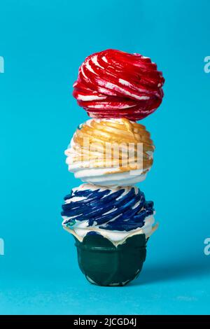Bunte Torte aus mehrfarbiger Glasur auf blauem Hintergrund. Kreatives Süßes. Schönes ungewöhnliches Dessert. Stockfoto