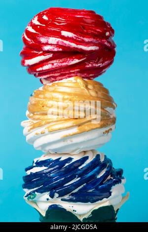 Bunte Kuchen oder Marschmalven mit mehrfarbigem Glasur auf blauem Hintergrund bedeckt. Kreatives Süßes. Schönes ungewöhnliches Dessert. Stockfoto
