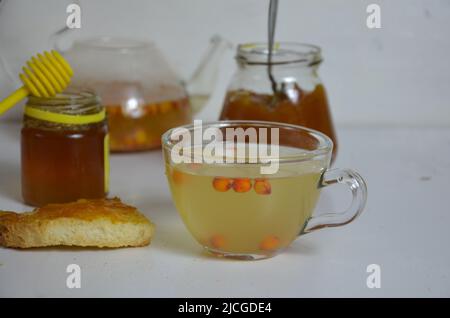 Die Idee des Schutzes und der Behandlung der Grippe mit Volksmitteln mit den gesunden Sanddornbeerenzweigen mit Beeren, mit Tee und Honig. Marmelade Stockfoto