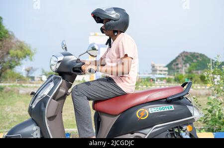 Mann fährt EV oder Elektroroller durch das Tragen von Helm auf der Straße - Konzept der Sicherheit, Technologie und Lifestyle. Stockfoto