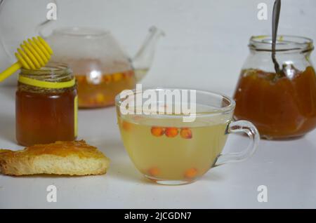 Die Idee des Schutzes und der Behandlung der Grippe mit Volksmitteln mit den gesunden Sanddornbeerenzweigen mit Beeren, mit Tee und Honig. Marmelade Stockfoto