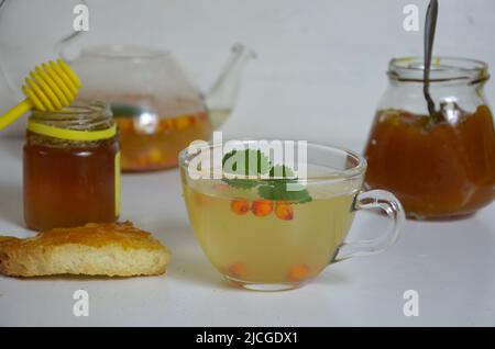 Die Idee des Schutzes und der Behandlung der Grippe mit Volksmitteln mit den gesunden Sanddornbeerenzweigen mit Beeren, mit Tee und Honig. Marmelade Stockfoto