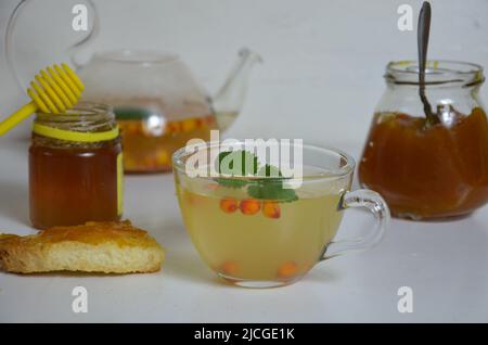 Die Idee des Schutzes und der Behandlung der Grippe mit Volksmitteln mit den gesunden Sanddornbeerenzweigen mit Beeren, mit Tee und Honig. Marmelade Stockfoto