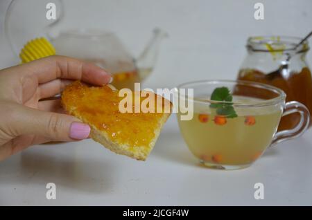 Die Idee des Schutzes und der Behandlung der Grippe mit Volksmitteln mit den gesunden Sanddornbeerenzweigen mit Beeren, mit Tee und Honig. Marmelade Stockfoto