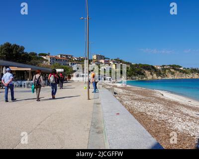 Menschen, die entlang der Spiaggia delle Ghiaie, dem öffentlichen Strand, Portoferraio, Elba, Provinz Livorno, Italien. Stockfoto