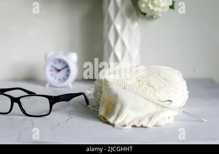Gläser, Garnknäuel und Stricknadeln auf dem Tisch. Strickkonzept mit Garnkugeln. Kreatives Hobby. Stockfoto