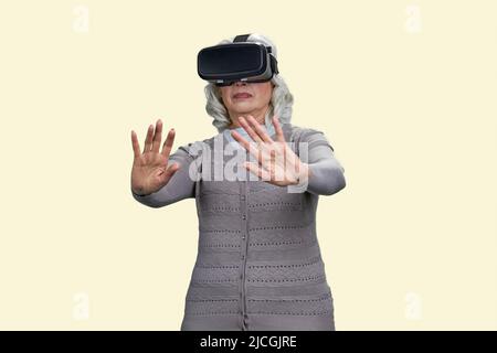 Die alte Dame war schockiert, als sie ein Virtual-Reality-Headset erlebte. Isoliert auf weißem Hintergrund. Stockfoto