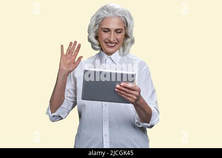 Lächelnde ältere Frau mit einem Videoanruf auf einem Tablet-pc. Isoliert auf weißem Hintergrund. Stockfoto