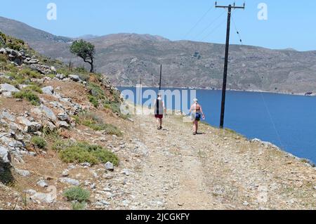 Zwei Wanderfrauen auf einem zerklüfteten und staubigen Pfad auf der Insel Tilos in der Nähe von Rhodos in Richtung Livadia. Frühjahr 2022. Mai Stockfoto