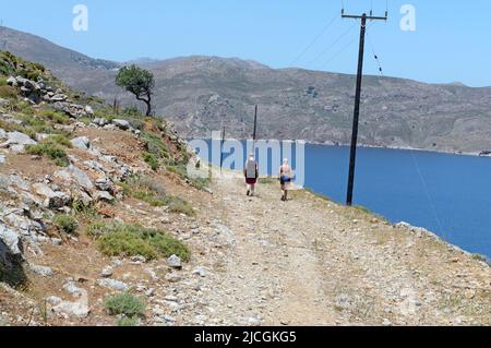 Zwei Wanderfrauen auf einem zerklüfteten und staubigen Pfad auf der Insel Tilos in der Nähe von Rhodos in Richtung Livadia. Frühjahr 2022. Mai Stockfoto