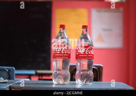 Zwei weiße Coca-Cola-Flaschen auf dem Tisch. Das beliebteste Getränk der Welt. Stockfoto