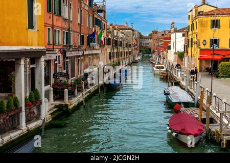 Blick auf Boote auf dem schmalen Kanal entlang alter, farbenfroher Häuser und typischer Straße in Venedig, Italien. Stockfoto