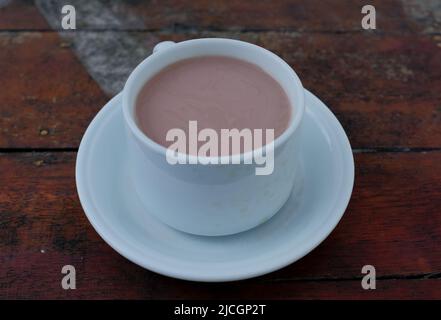 Warme Schokoladenmilch in weißer Tasse auf Holztisch Stockfoto