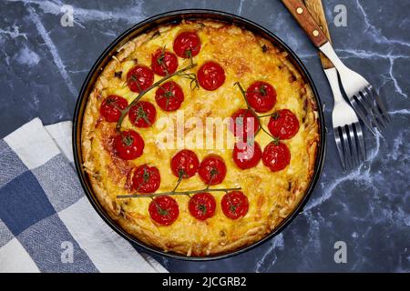 Köstliche Quiche mit gebackenen Tomaten auf einem Zweig und Huhn, gefüllt mit Rahm, Käse und Eiern. Kochen Sie zu Hause Stockfoto