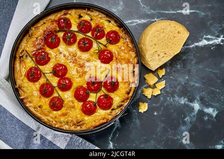 Pie mit gebackenen ganzen Kirschtomaten auf einem Zweig und Huhn, gefüllt mit Rahm, Käse und Eiern. Draufsicht Stockfoto