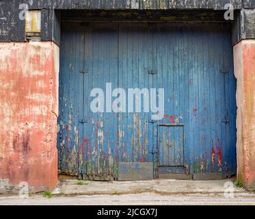 Große hölzerne Scheunentüren mit abblätternder blauer Farbe Stockfoto