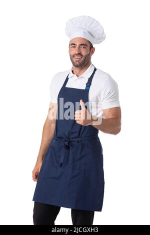 Porträt eines glücklichen jungen Köchin in Uniform stehend isoliert auf weißem Hintergrund. Die Kamera zeigt den Daumen nach oben. Stockfoto