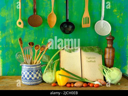 Frisches Gemüse, vegetarisches Kochbuch und Küchenutensilien. Gesundes Essen, Diät, vegetarisches Lebensmittelkonzept. Stockfoto