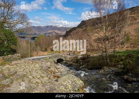 Wanderer Touristen Besucher Ashness Bridge und Skiddaw im Hintergrund Frühling späten Winter in der Nähe von Keswick Lake District National Park Cumbria England Großbritannien Stockfoto