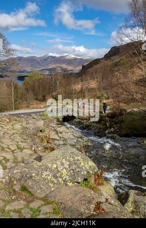 Wanderer Touristen Besucher Ashness Bridge und Skiddaw im Hintergrund Frühling späten Winter in der Nähe von Keswick Lake District National Park Cumbria England Großbritannien Stockfoto