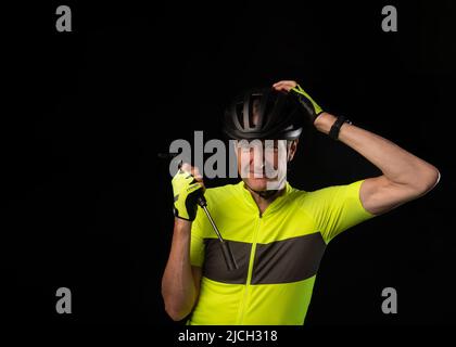 Radfahrer lächelt mit der Hand auf dem Kopf und hält eine Fahrradpumpe Stockfoto