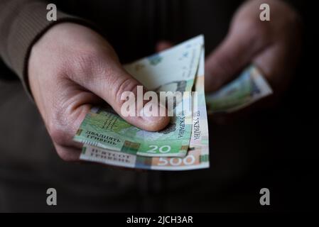 Weißer Mann, der ukrainische Geldscheine aus der Nähe gibt Stockfoto
