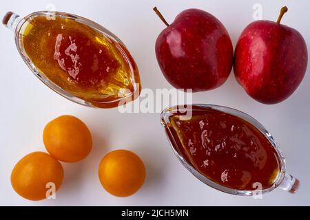 Apfel- und Kirschpflaumenkonfitüre in Glaswaren und Zutaten auf weißem Hintergrund. Draufsicht. Flach liegend. Stockfoto