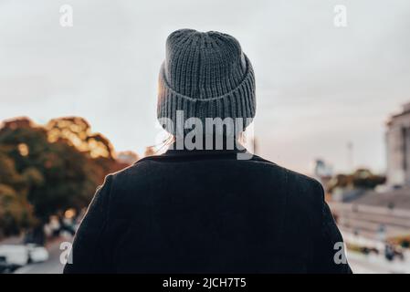 Eine junge Frau auf ihrem Rücken trägt eine Wollmütze. Winterkonzept Stockfoto