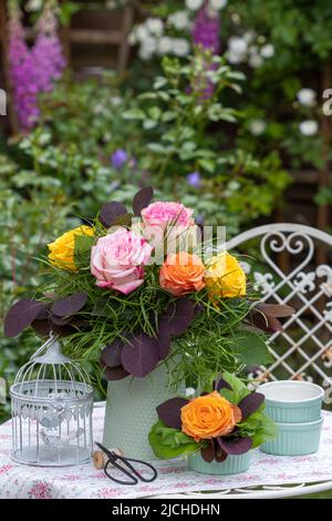 Strauß Rosen und rauchbuschige Blätter in Vintage Vase im Sommergarten Stockfoto