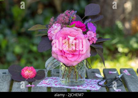 Bouquet von rosa Rosen und rauchigen Baumblättern im Garten Stockfoto