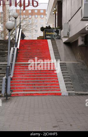 Rote Treppen, die mit Lichtmasten gesäumt sind, führen zu einem Schild mit Frank Sinatra darauf; in den Straßen im Zentrum von Minsk, Weißrussland Stockfoto