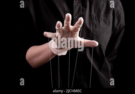 Hand in medizinischen Handschuh mit Schnüren an den Fingern. Täuschung in Medizin und Pharmazie, Verschwörungstheorie, Gesundheitsbetrug, Verbreitung falscher Informationen über Krankheiten, Medikamente. Hochwertige Fotos Stockfoto