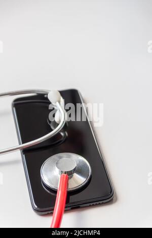 Das rote Stethoskop auf dem schwarzen Smartphone stellt Gesundheitsakten und digitale Patientenakten mit mobilen Geräten für die digitale Diagnose von Ärzten dar Stockfoto